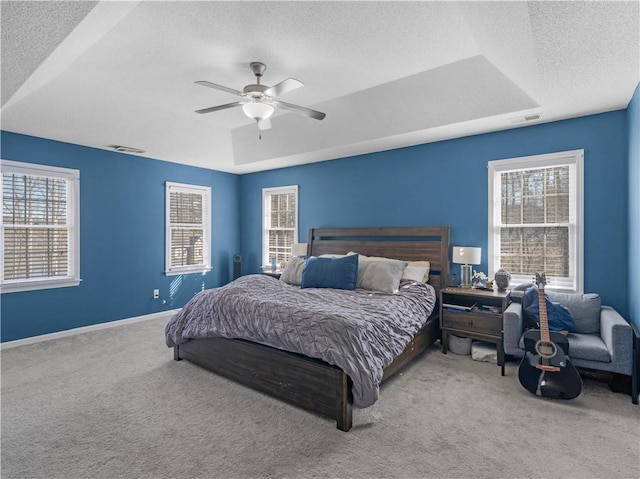 bedroom featuring carpet floors, a raised ceiling, visible vents, and baseboards