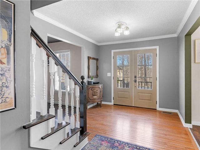 foyer featuring visible vents, stairs, french doors, hardwood / wood-style floors, and crown molding