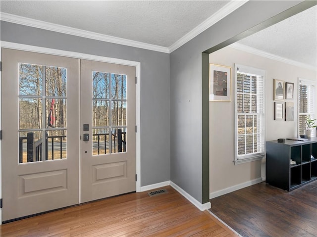 foyer entrance featuring ornamental molding, french doors, visible vents, and hardwood / wood-style floors