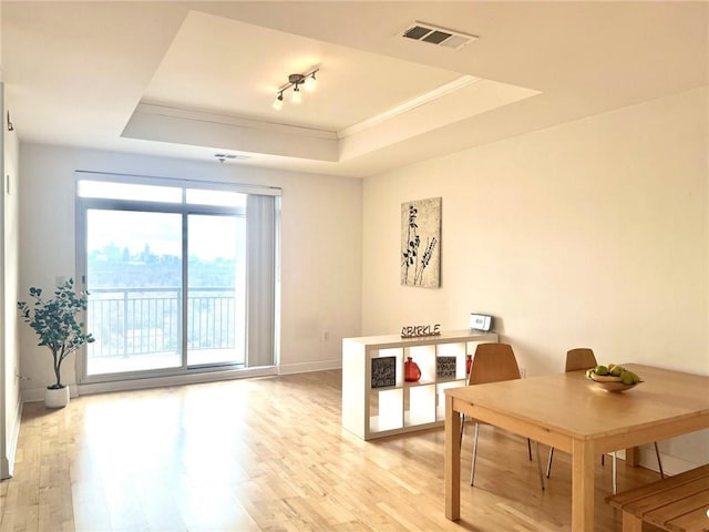 dining area with baseboards, visible vents, crown molding, a raised ceiling, and light wood-type flooring