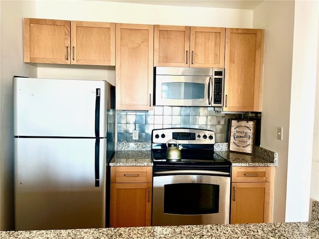 kitchen featuring light stone counters, tasteful backsplash, and appliances with stainless steel finishes