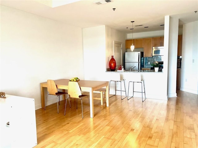 dining area with visible vents, baseboards, and light wood-style floors