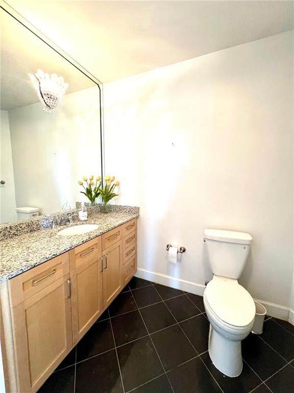 bathroom featuring tile patterned flooring, toilet, vanity, and baseboards