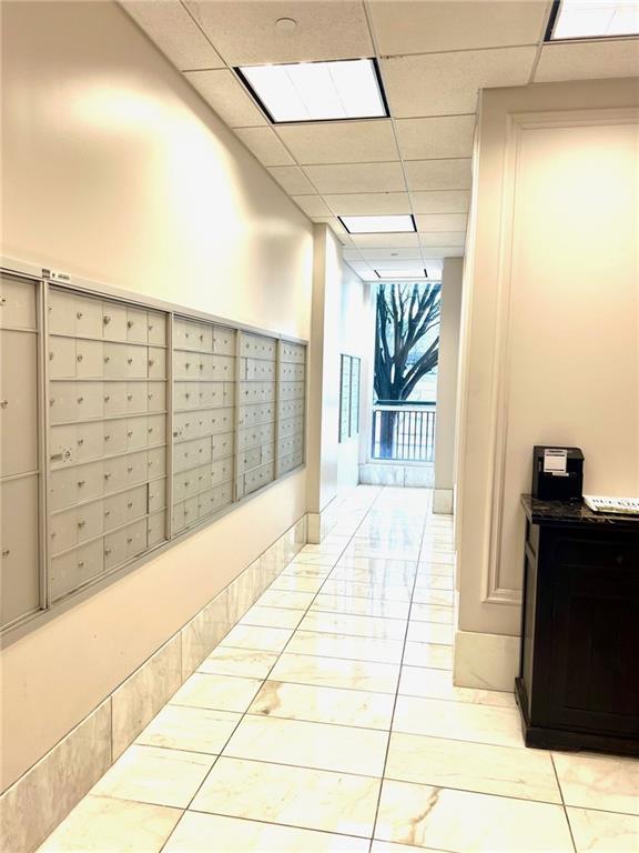 hall featuring a drop ceiling, mail area, and a wall of windows