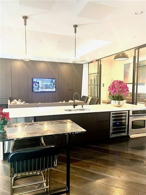 bar with oven, pendant lighting, beverage cooler, a sink, and hardwood / wood-style floors