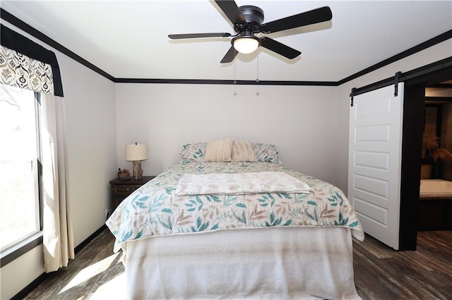 bedroom featuring a barn door, a ceiling fan, crown molding, and wood finished floors