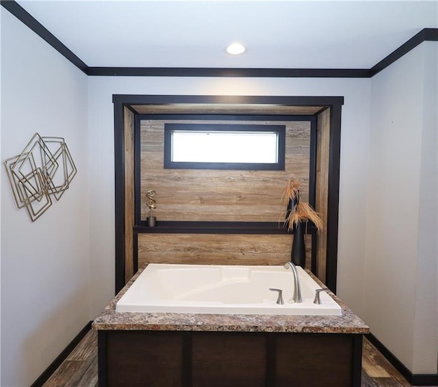 bathroom featuring baseboards, wood finished floors, a bath, and crown molding