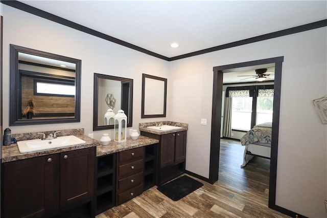 ensuite bathroom with two vanities, ornamental molding, a sink, ensuite bath, and wood finished floors