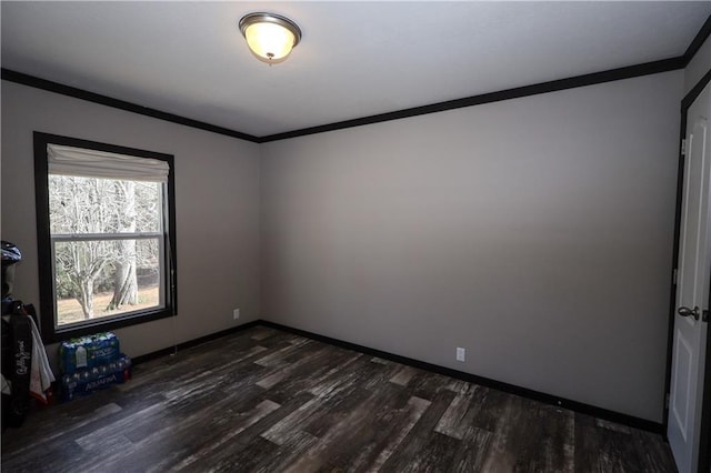 spare room with dark wood finished floors, crown molding, and baseboards