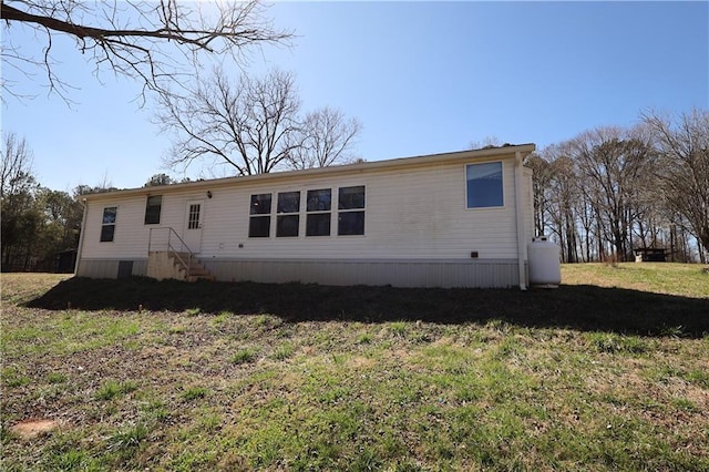 back of house featuring entry steps and a lawn