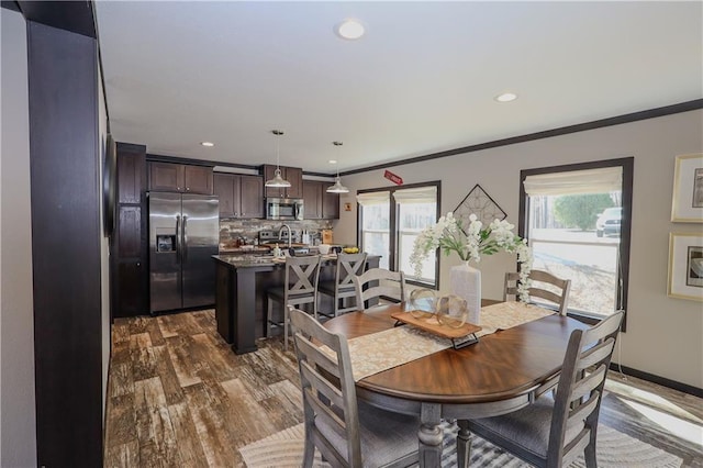 dining area with crown molding, baseboards, dark wood-style floors, and a healthy amount of sunlight