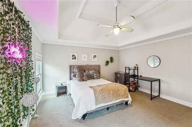 carpeted bedroom with a tray ceiling, ceiling fan, and crown molding