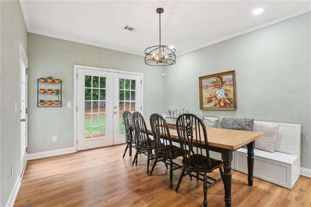 dining space with light wood-style flooring, french doors, baseboards, crown molding, and a chandelier