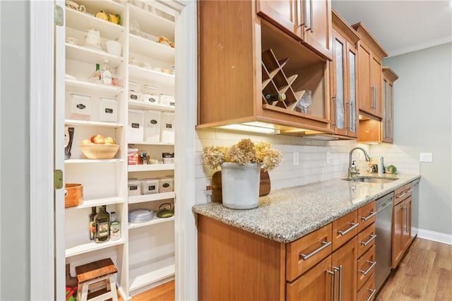 bar featuring a sink, stainless steel dishwasher, light wood finished floors, tasteful backsplash, and ornamental molding
