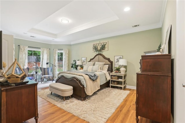 bedroom featuring a raised ceiling, light wood finished floors, crown molding, and recessed lighting