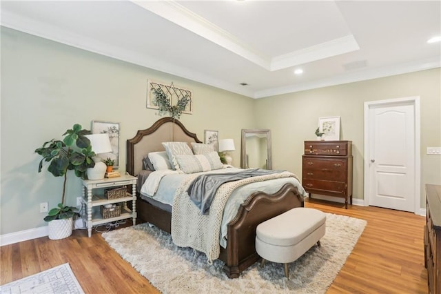 bedroom with light wood-style flooring, a raised ceiling, ornamental molding, baseboards, and recessed lighting