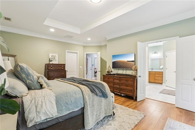 bedroom featuring crown molding, light wood-type flooring, recessed lighting, a raised ceiling, and connected bathroom