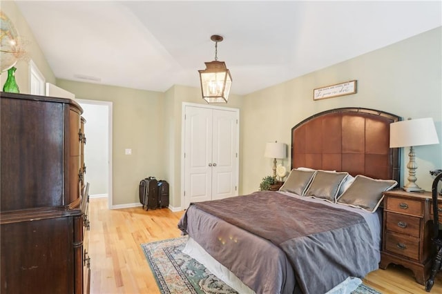 bedroom featuring light wood-type flooring, baseboards, and a closet