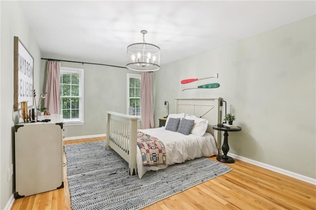 bedroom with wood finished floors, a chandelier, and baseboards