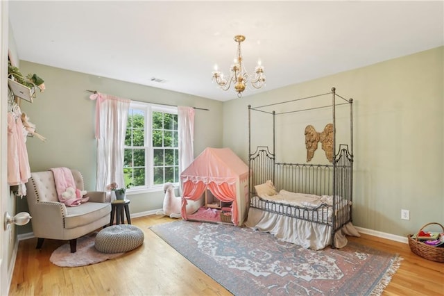 bedroom featuring a chandelier, wood finished floors, and baseboards
