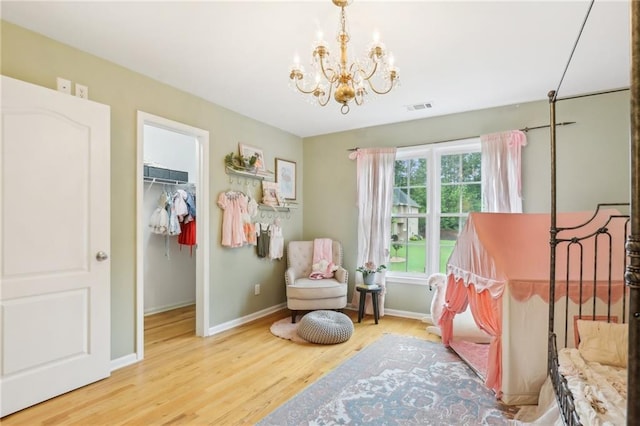 bedroom with a chandelier, baseboards, a spacious closet, and wood finished floors