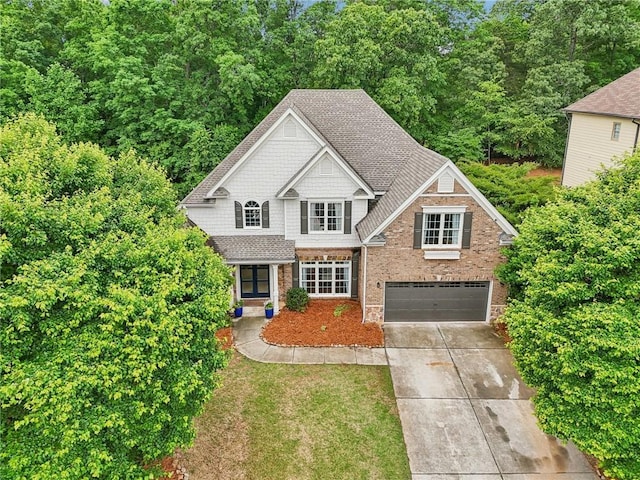 craftsman-style house featuring concrete driveway, a garage, brick siding, and roof with shingles