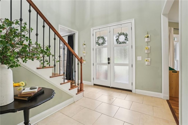 entryway featuring french doors, stairway, a high ceiling, baseboards, and tile patterned floors