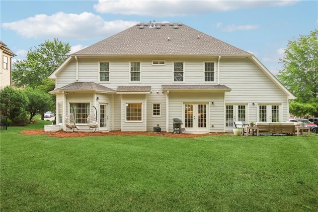 rear view of property featuring french doors, a yard, and roof with shingles