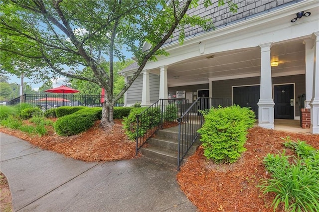 entrance to property with covered porch and fence