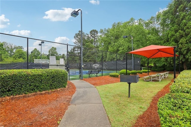 view of home's community featuring a tennis court and a gate