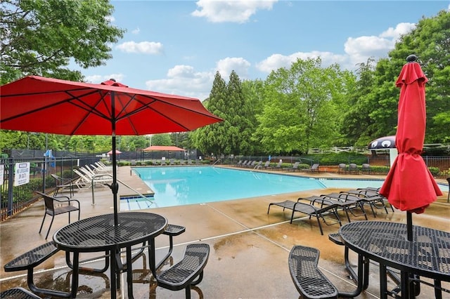 community pool with fence, a patio area, and view of scattered trees