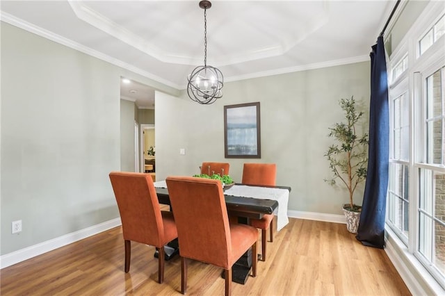 dining space with light wood-style floors, baseboards, a chandelier, ornamental molding, and a raised ceiling