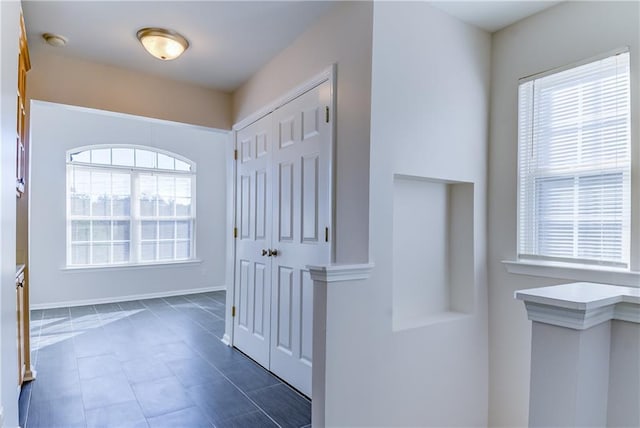 hall featuring dark tile patterned flooring and a wealth of natural light