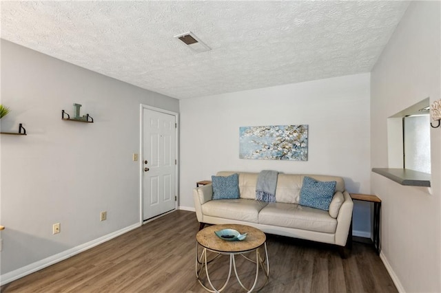 living room featuring dark wood-type flooring and a textured ceiling