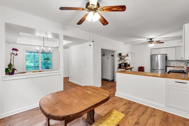 kitchen featuring freestanding refrigerator, refrigerator, a ceiling fan, light wood-type flooring, and baseboards