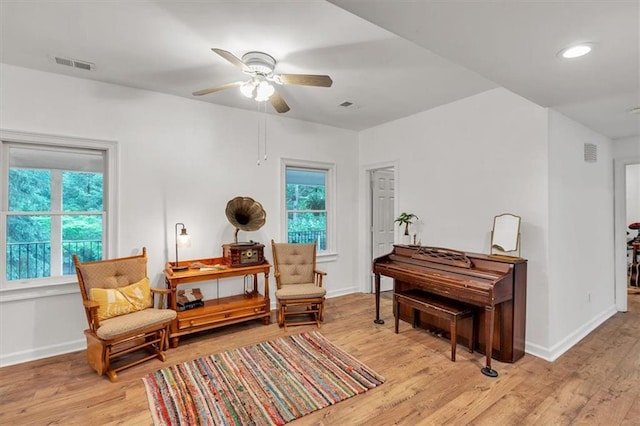 sitting room featuring ceiling fan, baseboards, and light wood finished floors