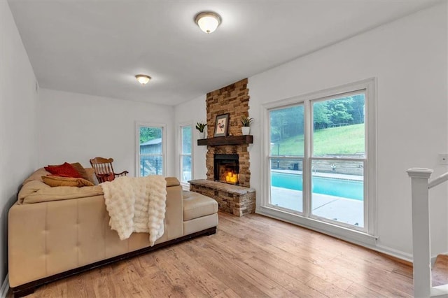 living room featuring light wood-style flooring, plenty of natural light, and a stone fireplace