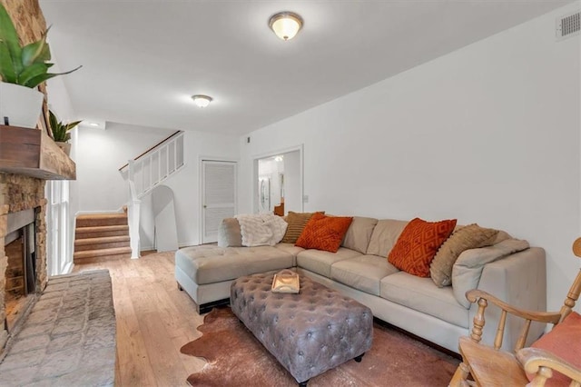 living room featuring hardwood / wood-style floors, stairs, and a brick fireplace