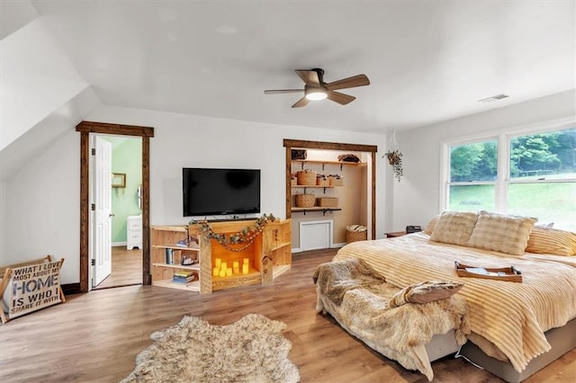 bedroom with wood finished floors, vaulted ceiling, ceiling fan, and ensuite bathroom
