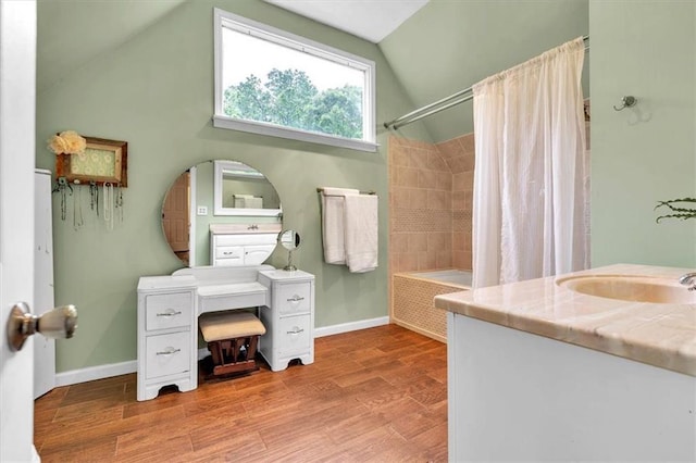 bathroom with lofted ceiling, wood finished floors, baseboards, shower / tub combo with curtain, and vanity