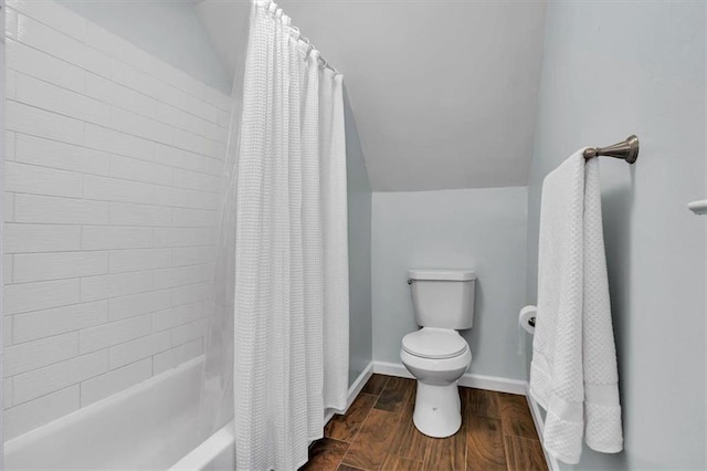 bathroom featuring toilet, wood finished floors, baseboards, and shower / tub combo
