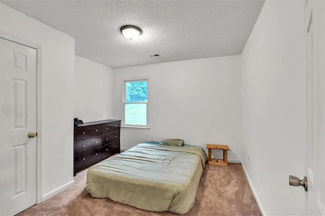 carpeted bedroom featuring a textured ceiling and baseboards
