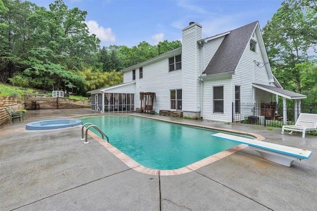 outdoor pool with a patio, a diving board, a sunroom, and view of wooded area