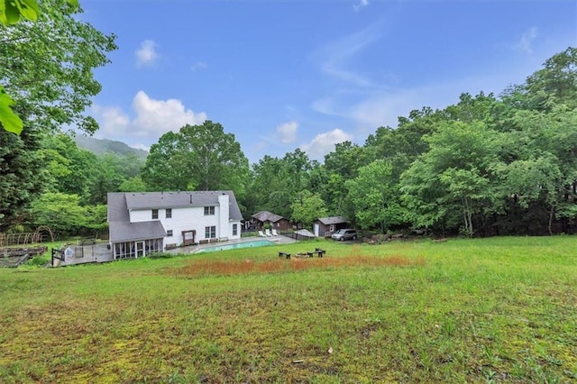 view of green lawn with a view of trees and an outdoor pool