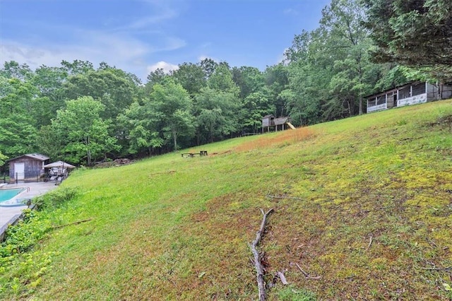 view of grassy yard with a wooded view and an outbuilding