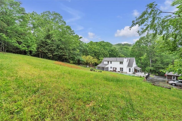 view of green lawn with a wooded view