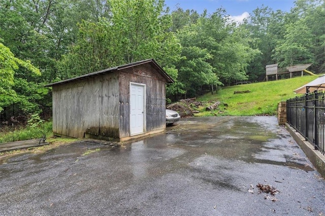 view of shed featuring fence and a view of trees