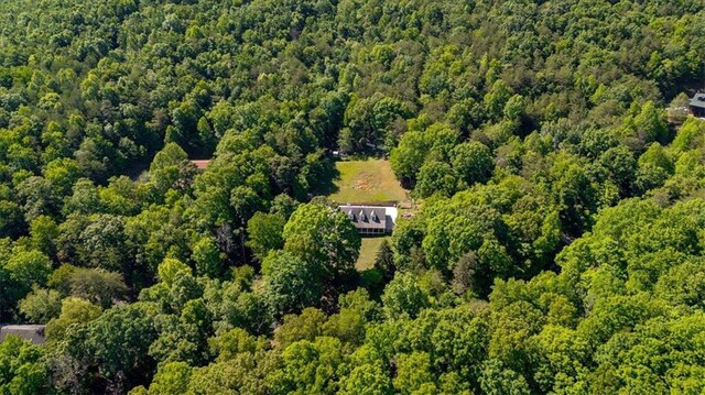aerial view of property and surrounding area featuring a forest
