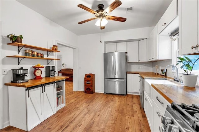kitchen featuring appliances with stainless steel finishes, open shelves, a ceiling fan, butcher block countertops, and a sink