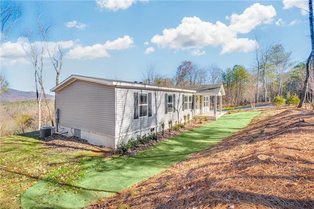 view of property exterior featuring covered porch, a yard, and central AC